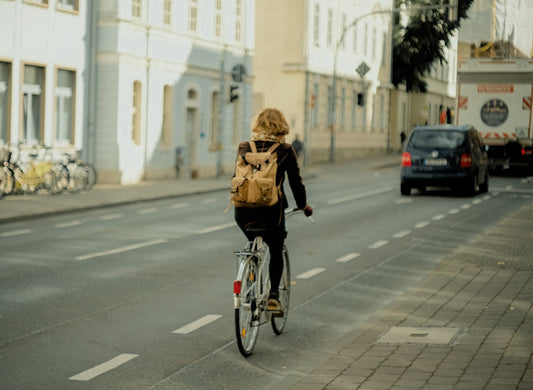 Frau in schwarzer Jacke fährt tagsüber mit dem Fahrrad auf der Straße.