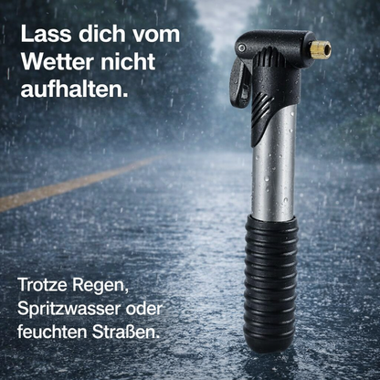 Mini-Fahrradpumpe auf nasser Straße im Regen stehend dargestellt.